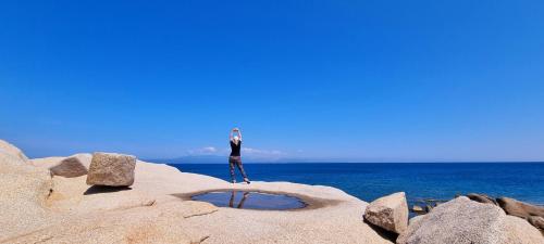 a person standing on a rock near the ocean at La villetta TRE PALME in Valledoria