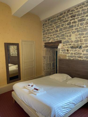 a bed in a room with a stone wall at Hôtel du Commerce in Semur-en-Auxois