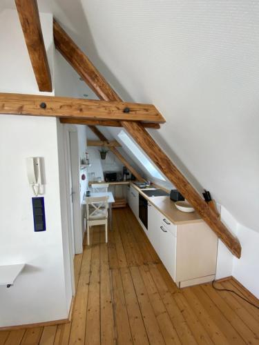 デュッセルドルフにあるMesseapartment Stockumの白いキャビネットと木製の梁がある屋根裏のキッチン