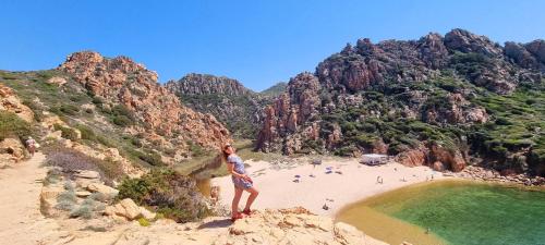 a woman standing on a cliff overlooking a beach at La villetta TRE PALME in Valledoria