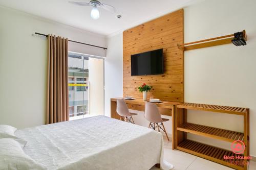 a bedroom with a bed and a desk and a tv at Estúdios 3 Praias in Ubatuba