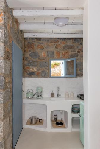 a kitchen with a sink and a stone wall at Nisides Suites in Livadi Astypalaias