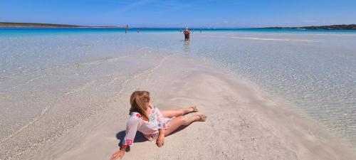 a little girl sitting on a beach in the water at La villetta TRE PALME in Valledoria