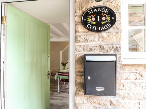 a clock on a stone wall next to a door at 1 Manor Cottage in Stow on the Wold