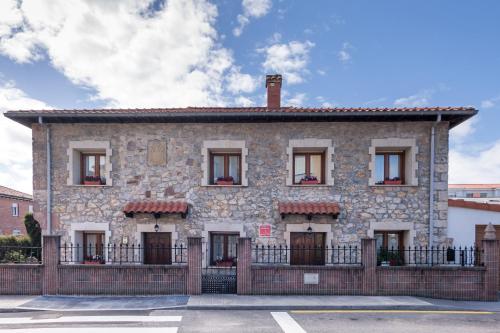 an old stone house with a fence in front of it at La casa de Virginia in Torrelavega