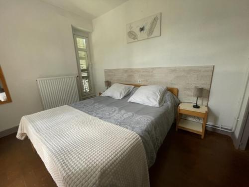 a bedroom with a bed and a lamp on a table at VILLA BONVOULOIR in Bagnères-de-Bigorre