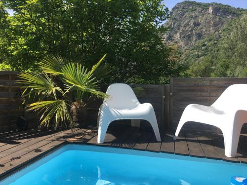 duas cadeiras brancas sentadas ao lado de uma piscina em Ô Lit' Chi em Hermillon