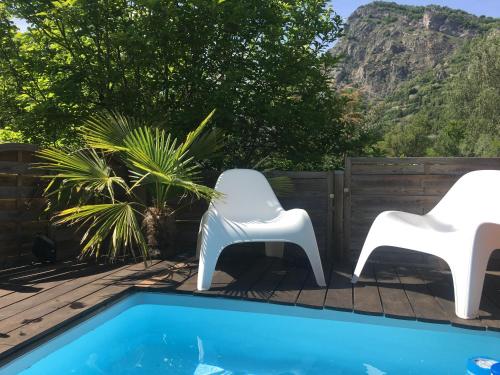 two white chairs sitting next to a swimming pool at Ô Lit' Chi in Hermillon