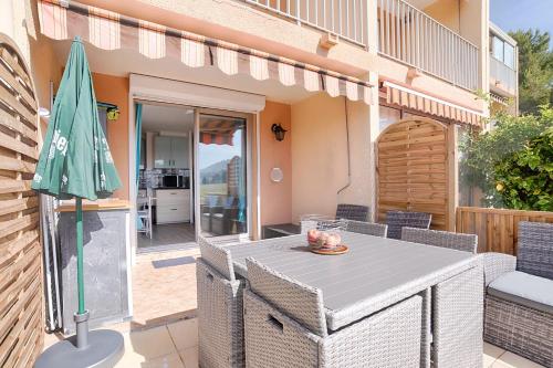 un patio avec une table et un parasol dans l'établissement Magnifique studio avec TERRASSE- PROCHE DE LA MER!, à Carqueiranne