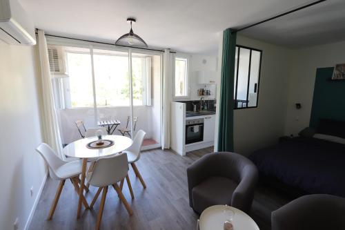Studio tout confort - Climatisation, parking, wifi في جيرو-لي-بان: غرفة معيشة صغيرة مع طاولة وكراسي