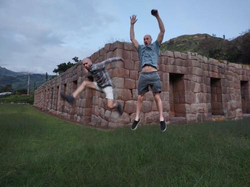 two men jumping in the air over a brick wall at Casona Mollepata in Mollepata