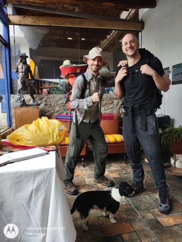 two men standing in a room with a dog at Casona Mollepata in Mollepata