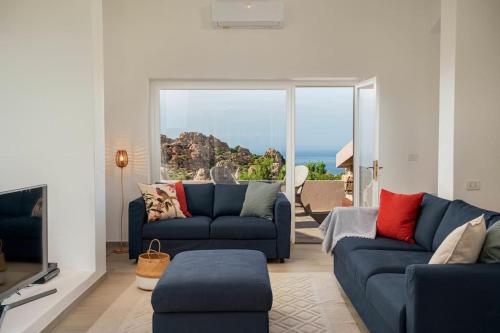 a living room with two blue couches and a large window at Villa Ester - A Sardinian Paradise in Costa Paradiso