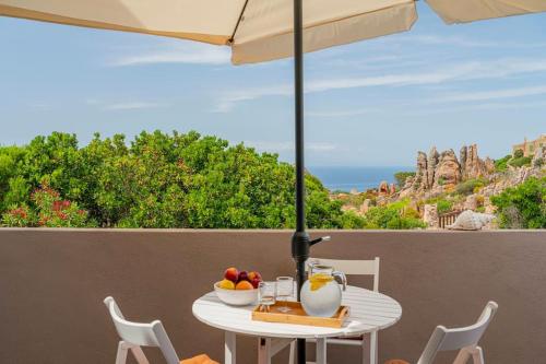 a white table with a bowl of fruit and an umbrella at Villa Ester - A Sardinian Paradise in Costa Paradiso
