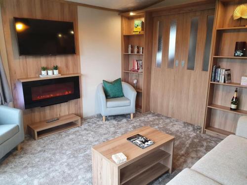 a living room with a tv and a couch and a chair at Beautiful Borders Cabin in Jedburgh