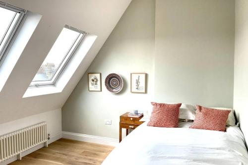 a bedroom with a white bed and two windows at Unique 2 Bedroom Penthouse Apartment in Kensal Rise in London