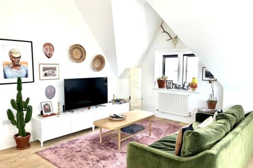 a living room with a green couch and a tv at Unique 2 Bedroom Penthouse Apartment in Kensal Rise in London