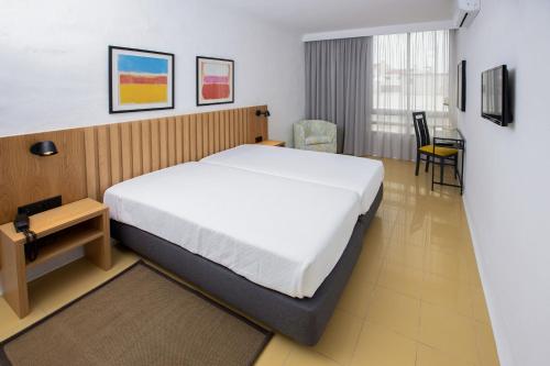 a bedroom with a bed and a table and chairs at Hotel Apartamento Foz Atlantida in Monte Gordo