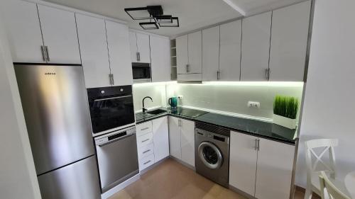 a kitchen with white cabinets and a stainless steel refrigerator at Casa Soñada - Dream House in Garrucha