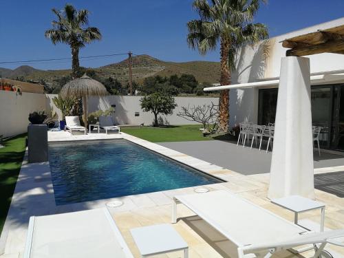 a swimming pool with chairs and a house at Casa David in Las Negras