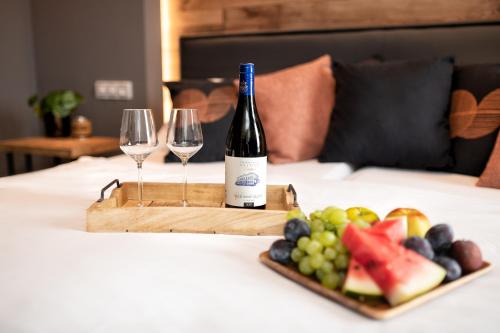 a bottle of wine and a tray of fruit on a bed at Wine & Wellness hotel Besední dům in Valtice