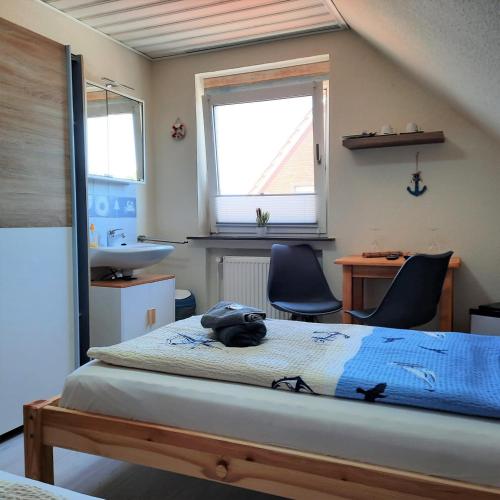 a bedroom with a bed and a sink and two chairs at Gästehaus Mia in Norddeich