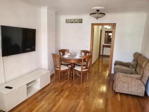 un soggiorno con tavolo, sedie e TV di Piso céntrico 2 habitaciones a escasos metros de Maria Pita a La Coruña