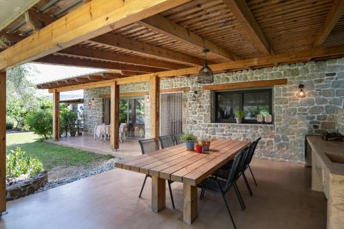 un patio al aire libre con mesa de madera y sillas en Villa Menie - Golden Fig Sykia lodge, en Paralia Sikias