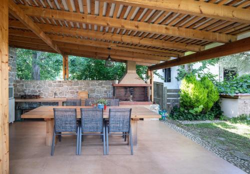 a patio with a wooden pergola with a table and chairs at Villa Menie - Golden Fig Sykia lodge in Paralia Sikias
