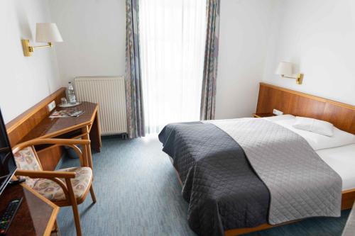a hotel room with a bed and a desk and a bed at Garni Hotel Maselheimer Hof in Maselheim