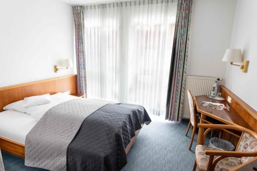 a hotel room with a bed and a desk and a window at Garni Hotel Maselheimer Hof in Maselheim