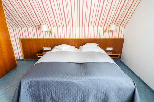 a bedroom with a large bed with a red stripped wall at Garni Hotel Maselheimer Hof in Maselheim