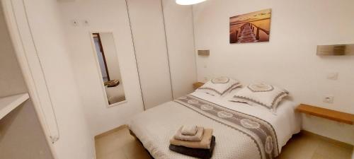 a small white bedroom with a bed with white sheets at le suquet quartier historique in Cannes