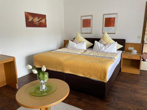 Cette chambre d'hôtel comprend un lit avec un vase de fleurs sur une table. dans l'établissement Gästehaus Ute Müller, à Wimbach