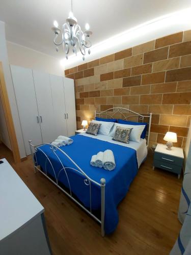 a bedroom with a blue bed with a brick wall at Casa vacanze - "O Tunnu" in Avola