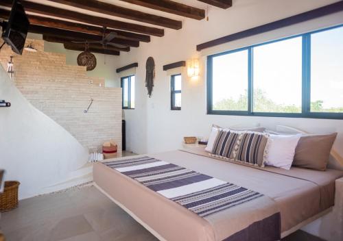 uma cama grande num quarto com janelas grandes em Villa Los Mangles Boutique Hotel em Ilha Holbox