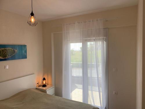 a bedroom with a bed and a large window at New Family Friendly Apartment in Nikiti