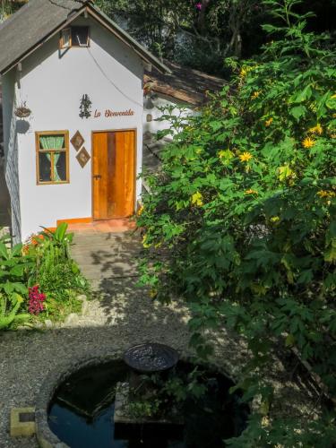 a small white building with a brown door and flowers at Finca Los Abuelos - La Planta in Concepción