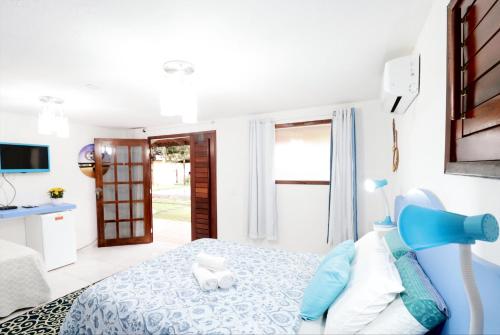a white bedroom with a blue bed and a door at Paracuru Kitefriends Lux Pousada in Paracuru
