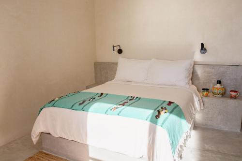 Una cama con una manta blanca y azul. en Topia Retreat - Piscina Suite Norte, en El Pescadero