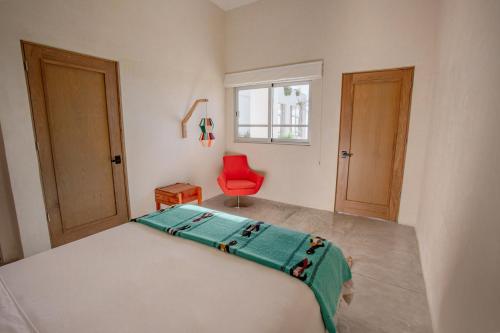 1 dormitorio con 1 cama y 1 silla roja en Topia Retreat - Piscina Suite Norte, en El Pescadero