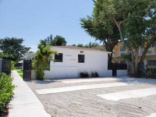 a white garage with a tree and a building at Casa Cuba in Little Havana, Brickell, Calle 8 and 10 minutes to the Beach FREE PARKING in Miami