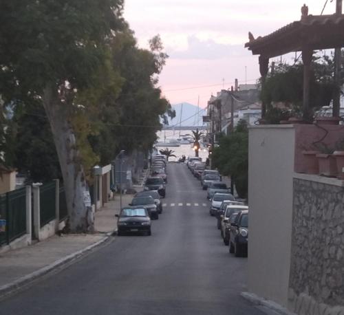 a street with cars parked on the sides of the road at Captain's Rooms in Aegina Town