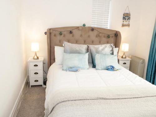 um quarto com uma grande cama branca com almofadas azuis em Cove House em Rhyl