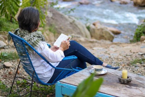 a woman sitting in a chair reading a book at a table at Finca Los Abuelos - La Planta in Concepción