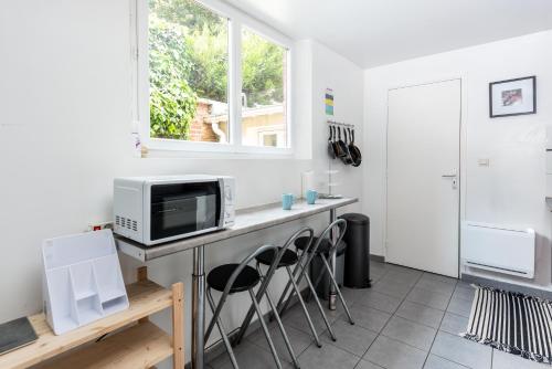 eine Küche mit einem Tisch, einer Mikrowelle und einem Fenster in der Unterkunft L'harmonie in Amiens