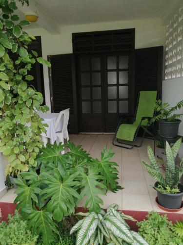 a patio with two green chairs and plants at La Douce Demeure in Matoury