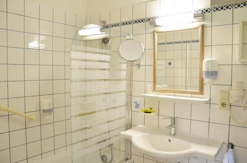 Baño blanco con lavabo y espejo en Seehotel Huber en Sankt Gilgen