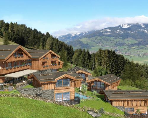 a house on top of a hill with a mountain at ZAGLGUT HOTEL-CHALETS Wellness & Views with Summer Card Included in Kaprun