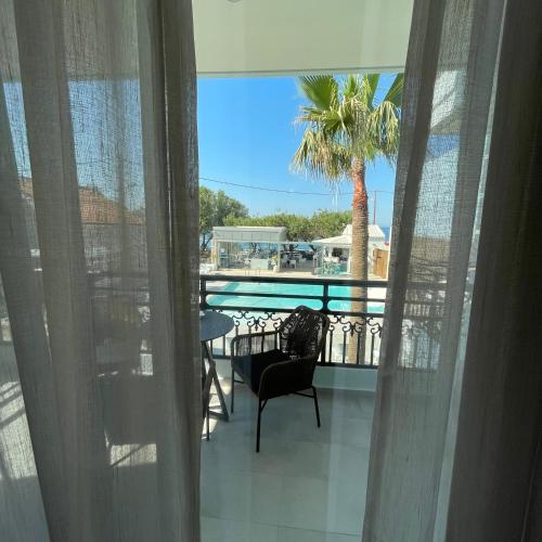 a view of a balcony with a table and a palm tree at Alkionides Seaside Hotel in Plataniás
